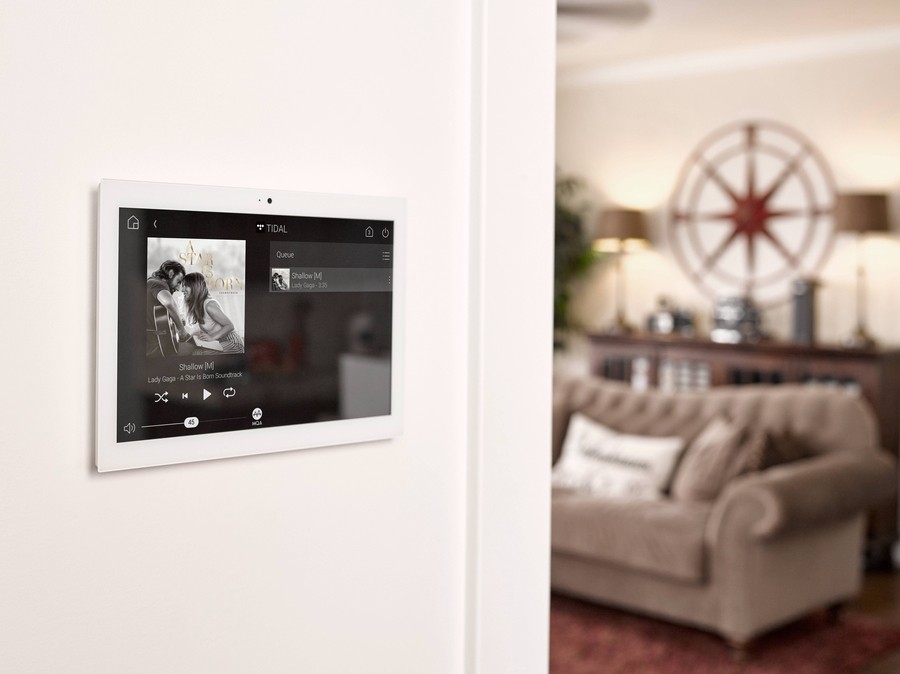 Wall-mounted touchpad in the hallway outside a bedroom shows Lady Gaga’s Shadow playing in the whole home audio system. 