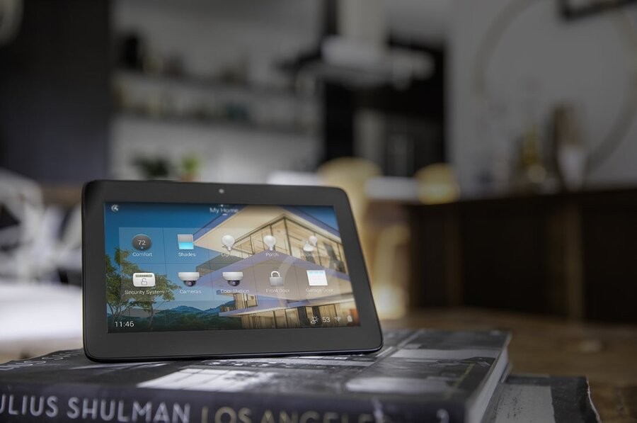 A Control4 interface on a tablet propped up on stacked books showcasing a smart home system’s solutions