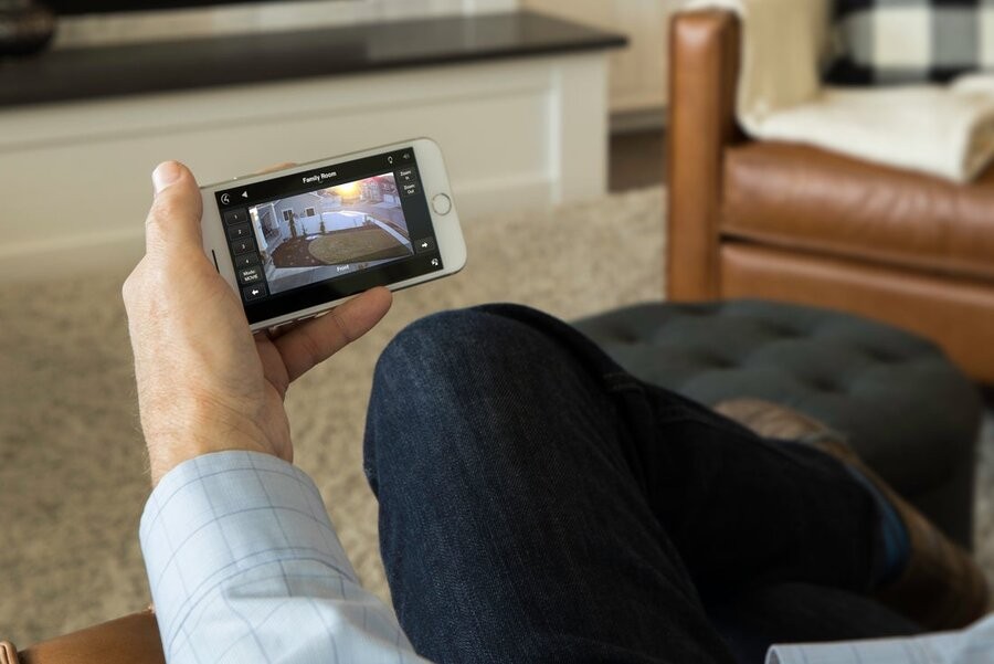 A man is viewing his home via a home security and surveillance system.