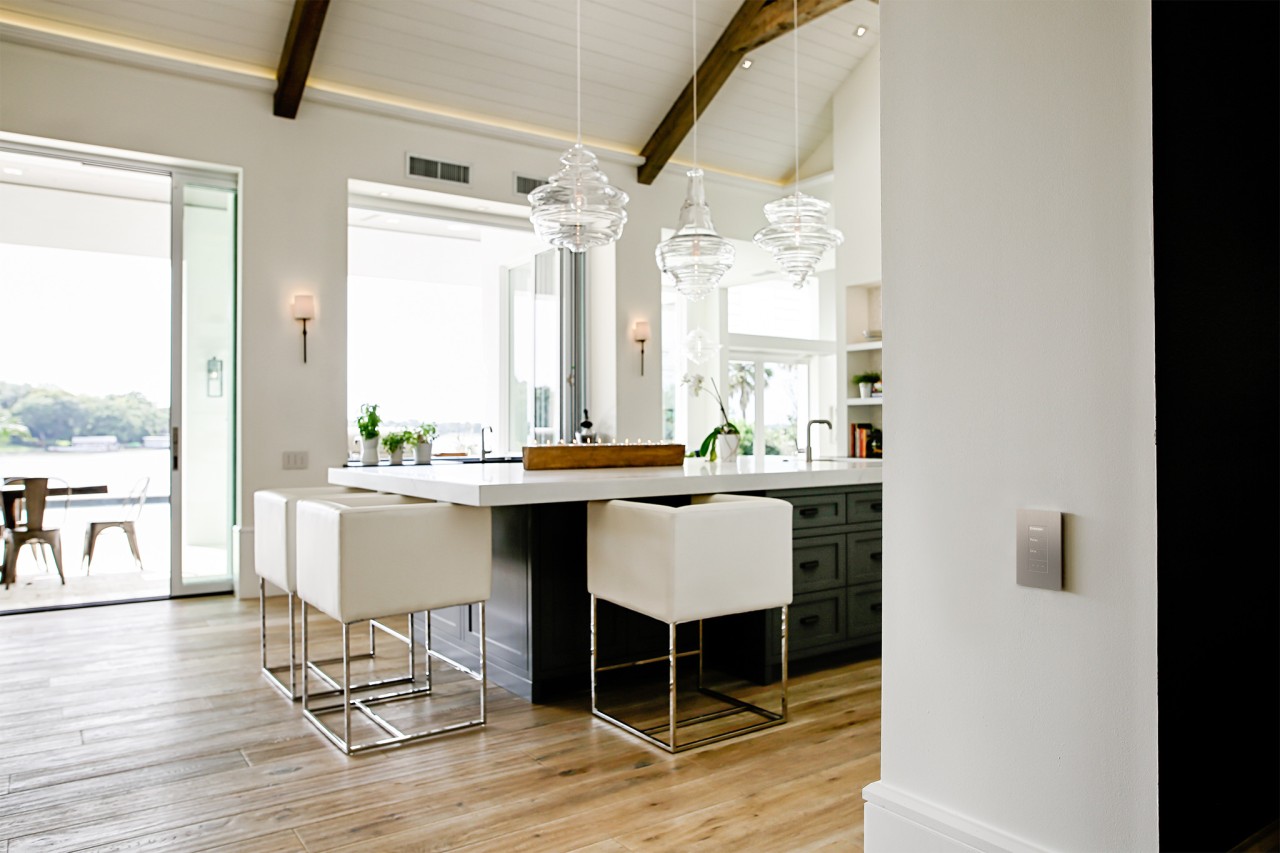 A kitchen area with sunlight coming in through the windows and a Lutron keypad on the wall.