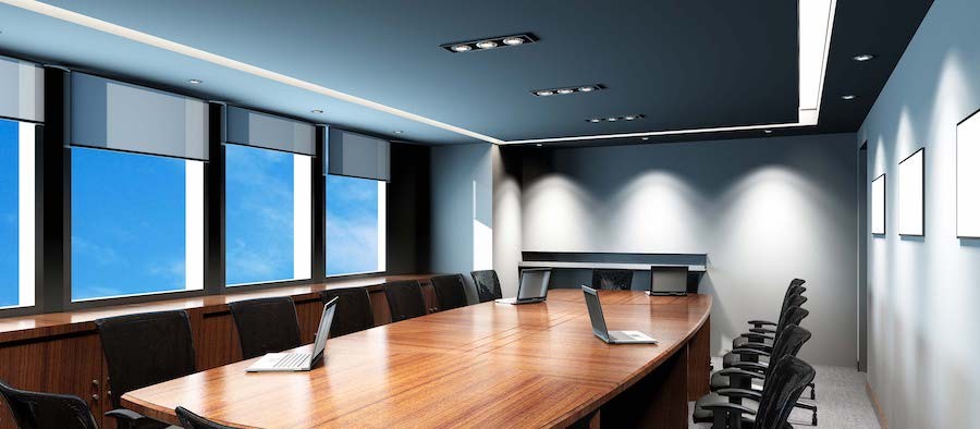 upscale conference room table with four laptops on the table and large windows in the background.