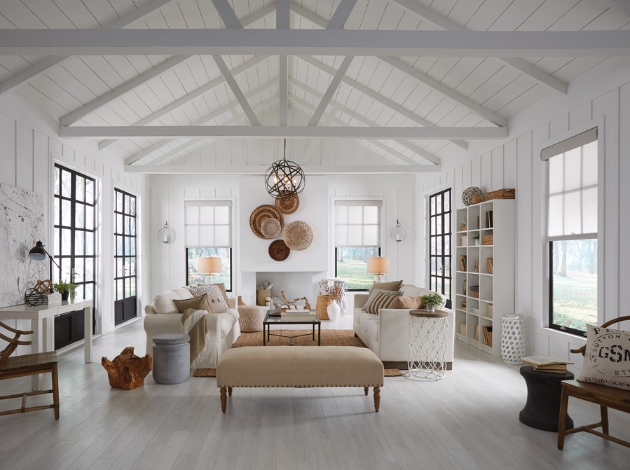 A well-lit living room with white walls and three sofas. 