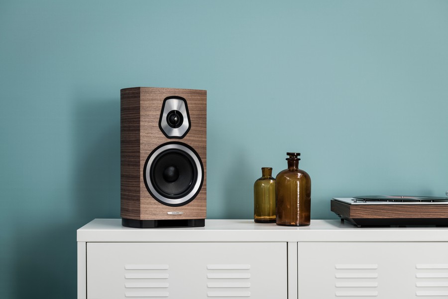 Wood finish Sonetto bookshelf speaker sitting on a counter alongside a turntable.