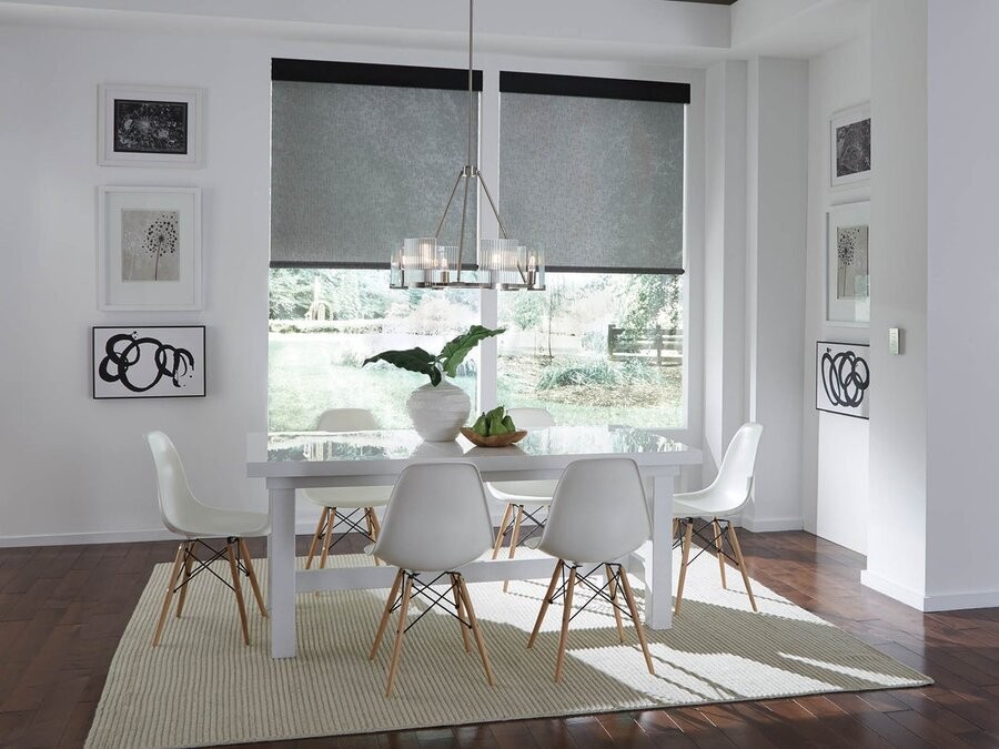 A dining table illuminated by a Lutron lighting control system and motorized shades in the windows. 